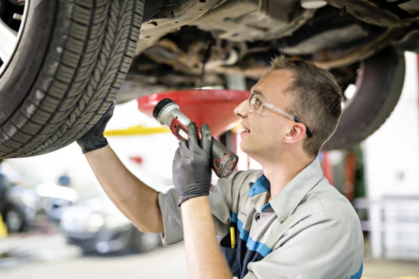Stilig mekaniker jobb i uniform som arbetar på bil — Stockfoto