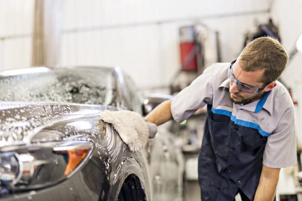 Człowiek w pracy sprzątanie samochodu na myjni samochodowej — Zdjęcie stockowe