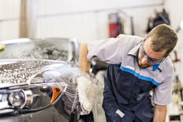 L'uomo a lavoro pulisce l'automobile all'atto di autolavaggio — Foto Stock