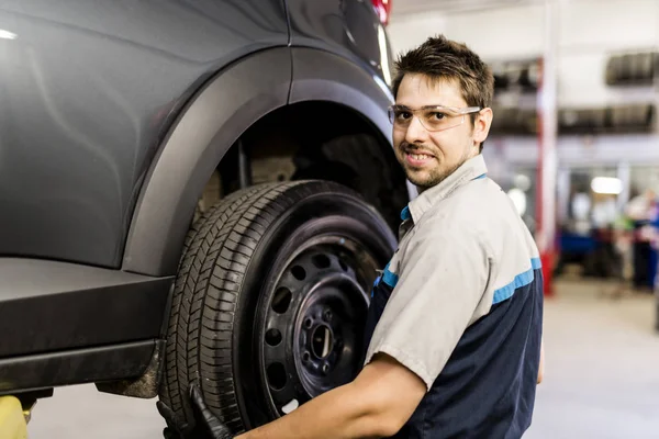 Knappe monteur baan in uniform werken op auto — Stockfoto