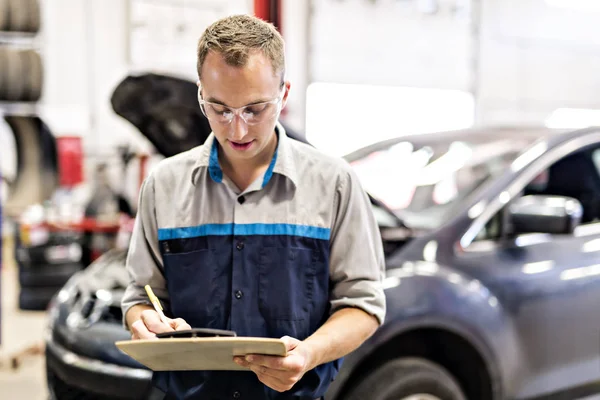 Knappe monteur baan in uniform werken op auto — Stockfoto