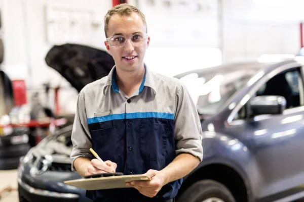 Handsome mechanic job in uniform working on car — Stock Photo, Image