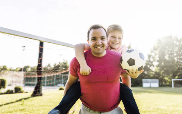 Hombre con niño jugando al fútbol afuera en el campo —  Fotos de Stock