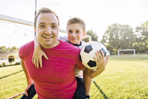 Uomo con bambino che gioca a calcio fuori sul campo — Foto Stock