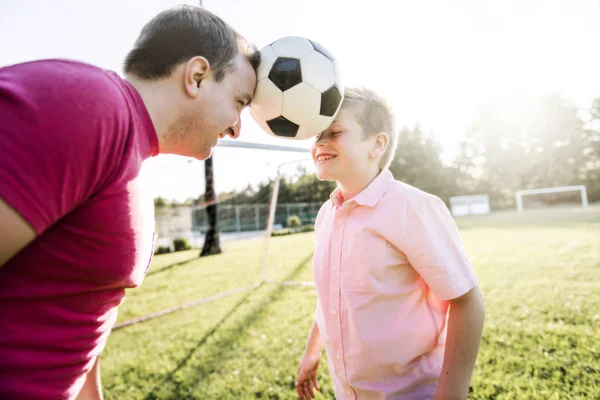 Hombre con niño jugando al fútbol afuera en el campo —  Fotos de Stock