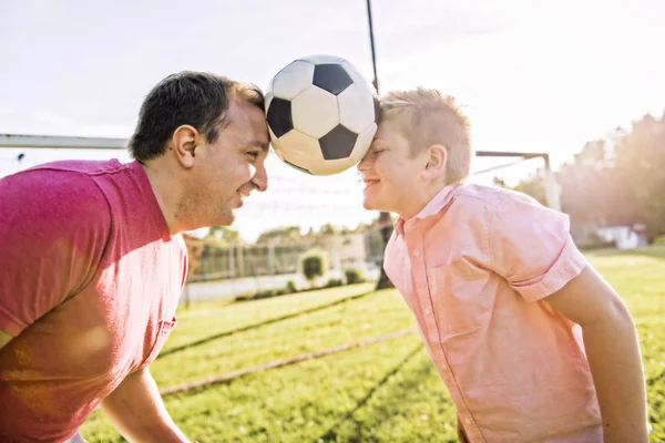 Hombre con niño jugando al fútbol afuera en el campo —  Fotos de Stock