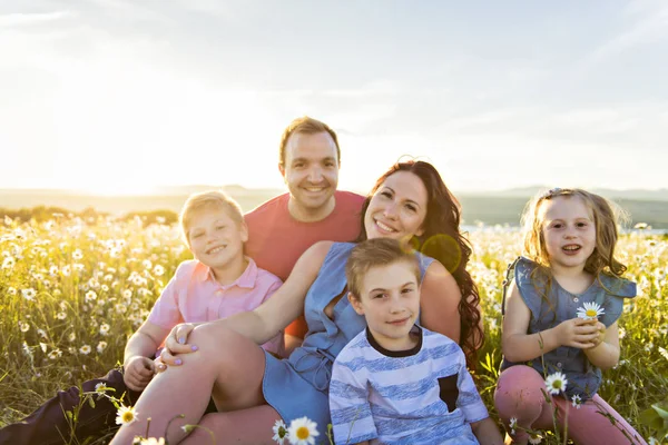 Gelukkige familie plezier op daisy veld bij zonsondergang — Stockfoto