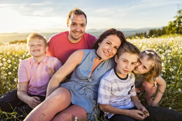 Glückliche Familie hat Spaß auf dem Gänseblümchenfeld bei Sonnenuntergang — Stockfoto