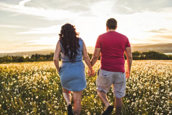 Man en vrouw op het gebied van daisy bij zonsondergang — Stockfoto