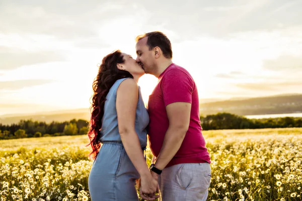 Mann und Frau auf dem Gänseblümchenfeld bei Sonnenuntergang — Stockfoto