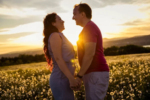 Mann und Frau auf dem Gänseblümchenfeld bei Sonnenuntergang — Stockfoto