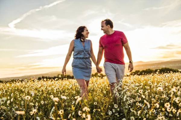 Homme et femme sur le champ de marguerites au coucher du soleil — Photo