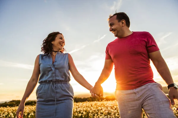 Man and woman on the daisy field at sunset — Stock Photo, Image