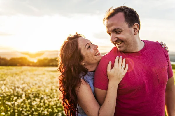 Man and woman on the daisy field at sunset — Stock Photo, Image