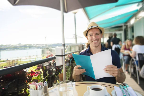 Молодой человек сидит турист сидеть на завтрак с кофе холдинг меню — стоковое фото