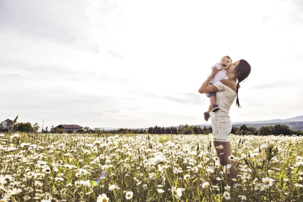 Kisfiú, és ő élvezi a szabadban mező százszorszép virág motherr — Stock Fotó