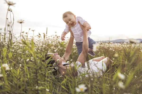 Liten pojke och hans motherr njuter utomhus i fält av daisy blommor — Stockfoto