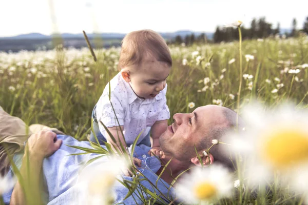 Liten pojke och hans far njuter utomhus i fält av daisy blommor — Stockfoto
