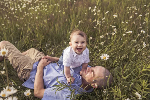 Petit garçon et son père profiter à l'extérieur dans le domaine des fleurs de marguerite — Photo