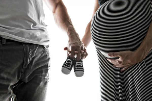 Mulher grávida e homem segurando sapatos de bebê — Fotografia de Stock