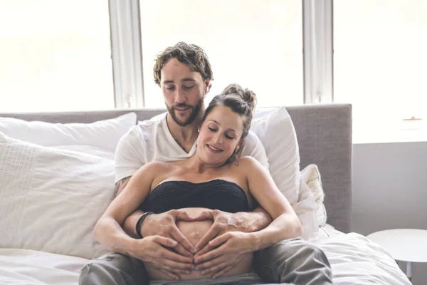 Uomo con donna incinta a letto a casa divertendosi — Foto Stock