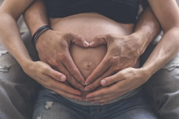 Primer plano de la forma del corazón de un par de manos juntas en el vientre de las mujeres embarazadas —  Fotos de Stock