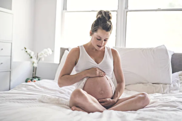 Glad graviditet sitter på sängen hemma — Stockfoto