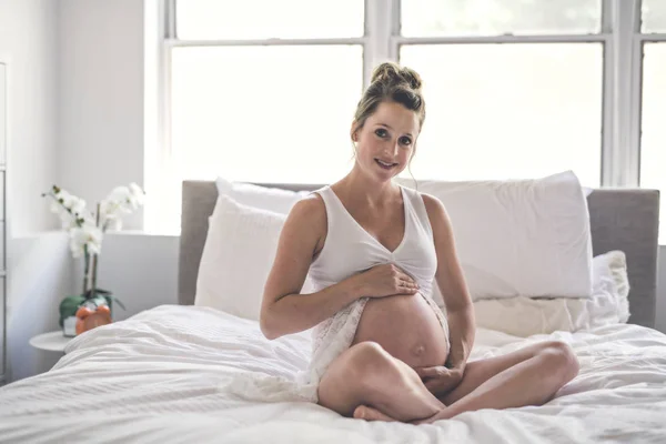 Feliz embarazo sentado en la cama en casa —  Fotos de Stock