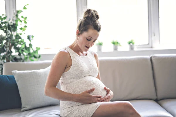 Glad graviditet sitter på soffan hemma — Stockfoto