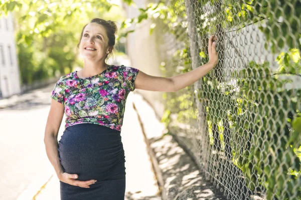 Retrato de una mujer embarazada feliz y orgullosa sobre fondo urbano —  Fotos de Stock