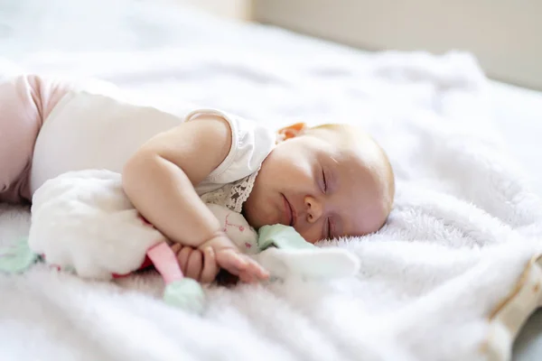 Adorabile bambina di due mesi che si rilassa in camera da letto su una coperta a maglia in una mattina di sole — Foto Stock