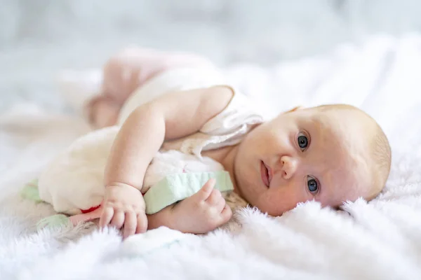 Adorabile bambina di due mesi che si rilassa in camera da letto su una coperta a maglia in una mattina di sole — Foto Stock
