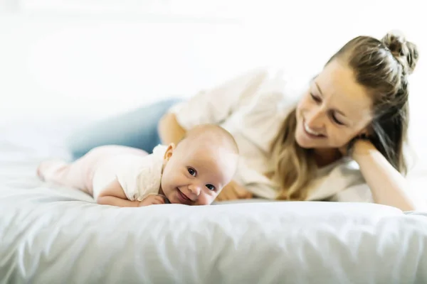 Retrato de una hermosa madre con su bebé de 2 meses en el dormitorio — Foto de Stock