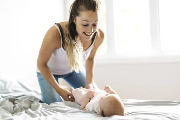 Retrato de una hermosa madre con su bebé de 2 meses en el dormitorio — Foto de Stock