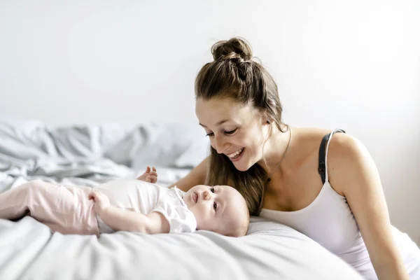 Retrato de una hermosa madre con su bebé de 2 meses en el dormitorio — Foto de Stock