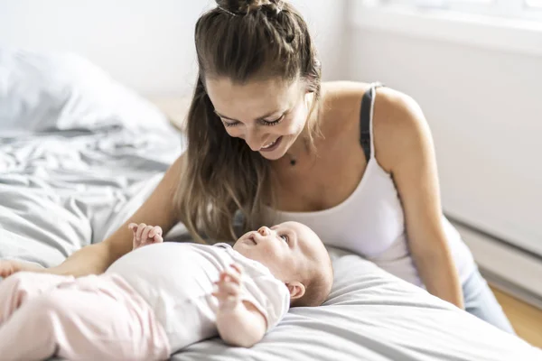 Retrato de una hermosa madre con su bebé de 2 meses en el dormitorio — Foto de Stock