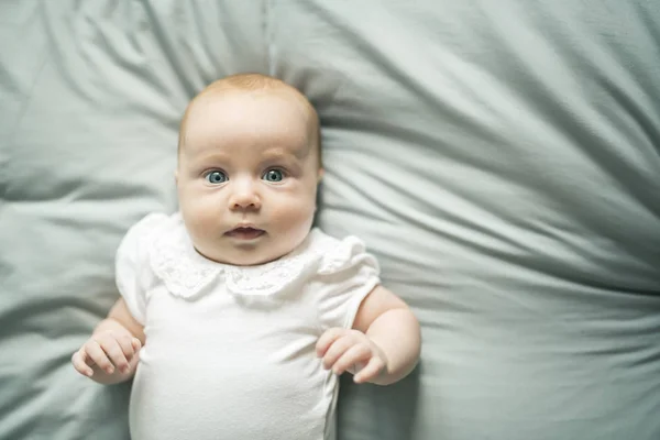 Adorabile bambina di due mesi che si rilassa in camera da letto su una coperta a maglia in una mattina di sole — Foto Stock