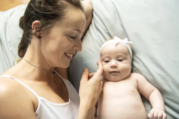 Портрет красивой матери с двухмесячным ребенком в спальне — стоковое фото