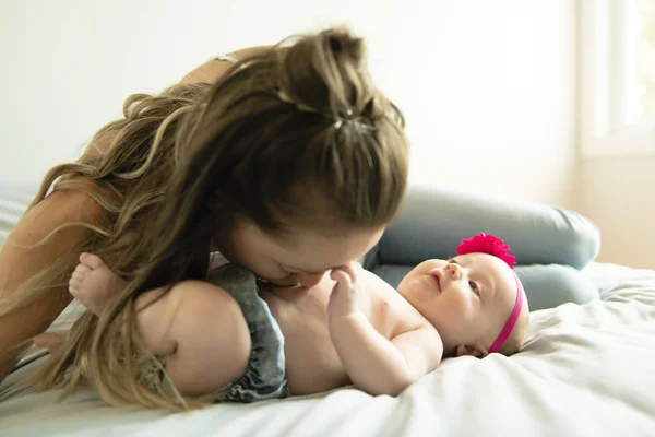 Portret van een mooie moeder met haar 2 maanden oude baby in de slaapkamer — Stockfoto