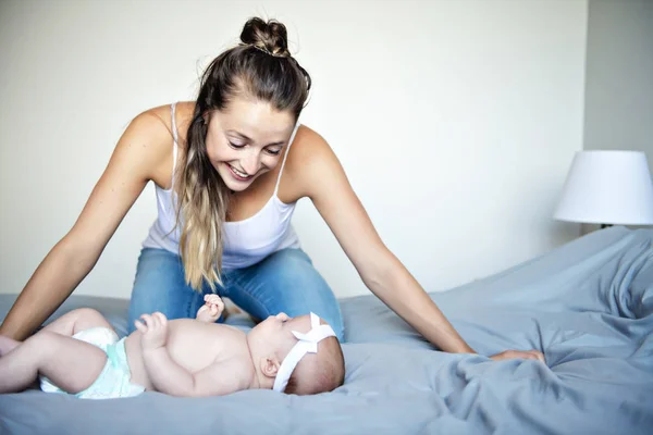 Портрет красивой матери с двухмесячным ребенком в спальне — стоковое фото
