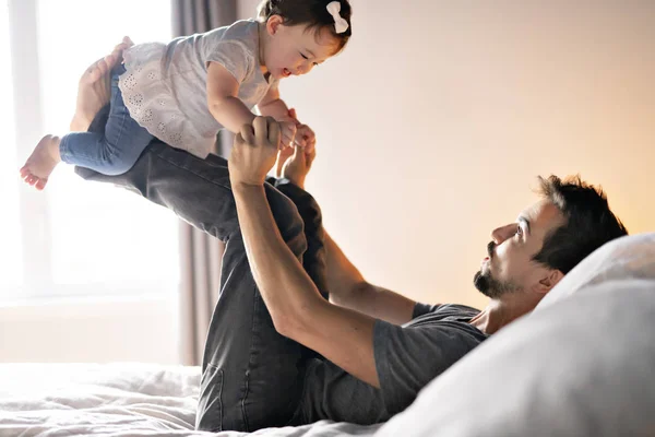 Padre joven con niña en la cama en casa — Foto de Stock