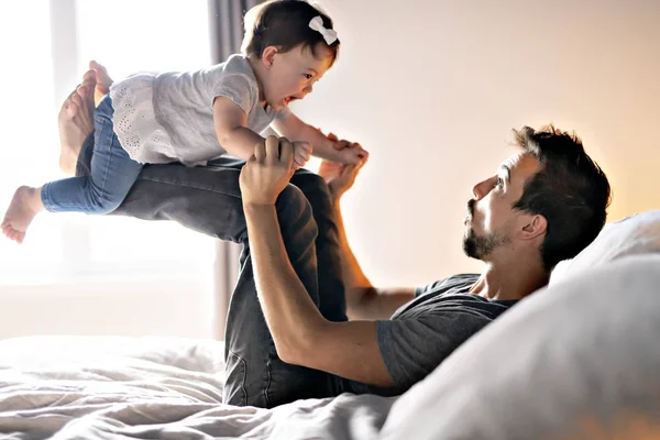 Padre joven con niña en la cama en casa — Foto de Stock