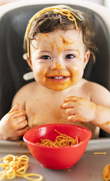 Child girl, eating spaghetti for lunch and making a mess at home in kitchen — Stock Photo, Image