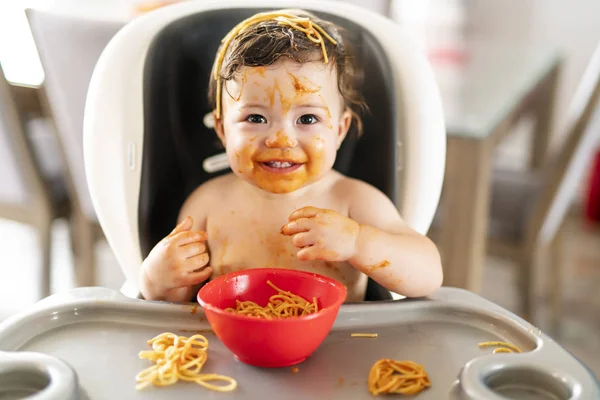 Niña, comer espaguetis para el almuerzo y hacer un lío en casa en la cocina — Foto de Stock