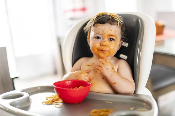 Niña, comer espaguetis para el almuerzo y hacer un lío en casa en la cocina — Foto de Stock