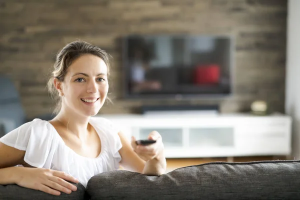 リビングルームでテレビを見ている若い女性 — ストック写真