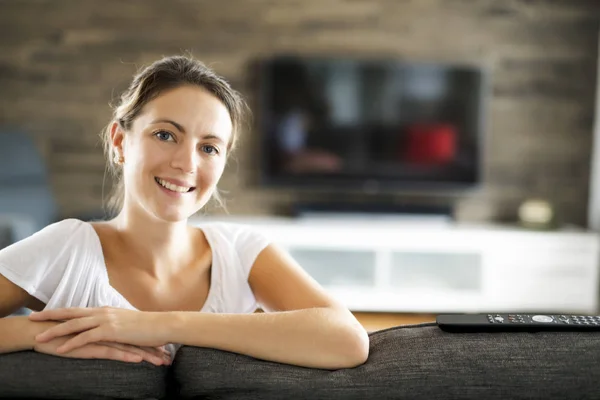 Jonge vrouw kijkt TV in de woonkamer — Stockfoto