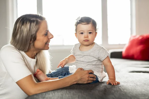 Mère et bébé fille joue à la maison sur le canapé — Photo