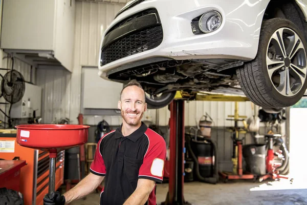 Knappe mechanic gebaseerd op auto in auto reparatiewerkplaats — Stockfoto