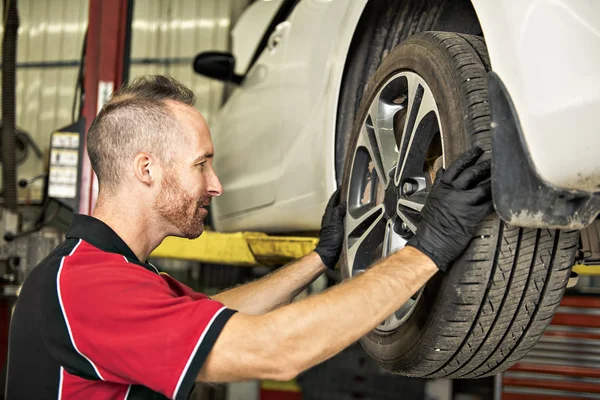 Knappe mechanic gebaseerd op auto in auto reparatiewerkplaats — Stockfoto